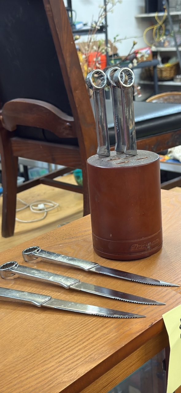 Three Snap-on steak knives with wrench handles on a wooden table.