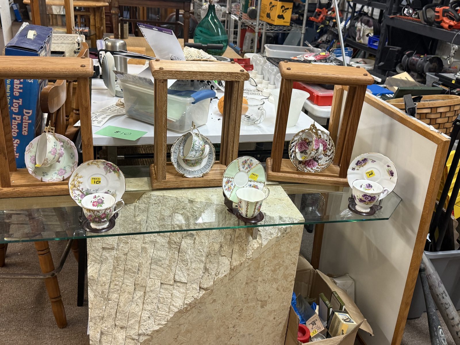 Floral teacups and saucers displayed on a glass table.